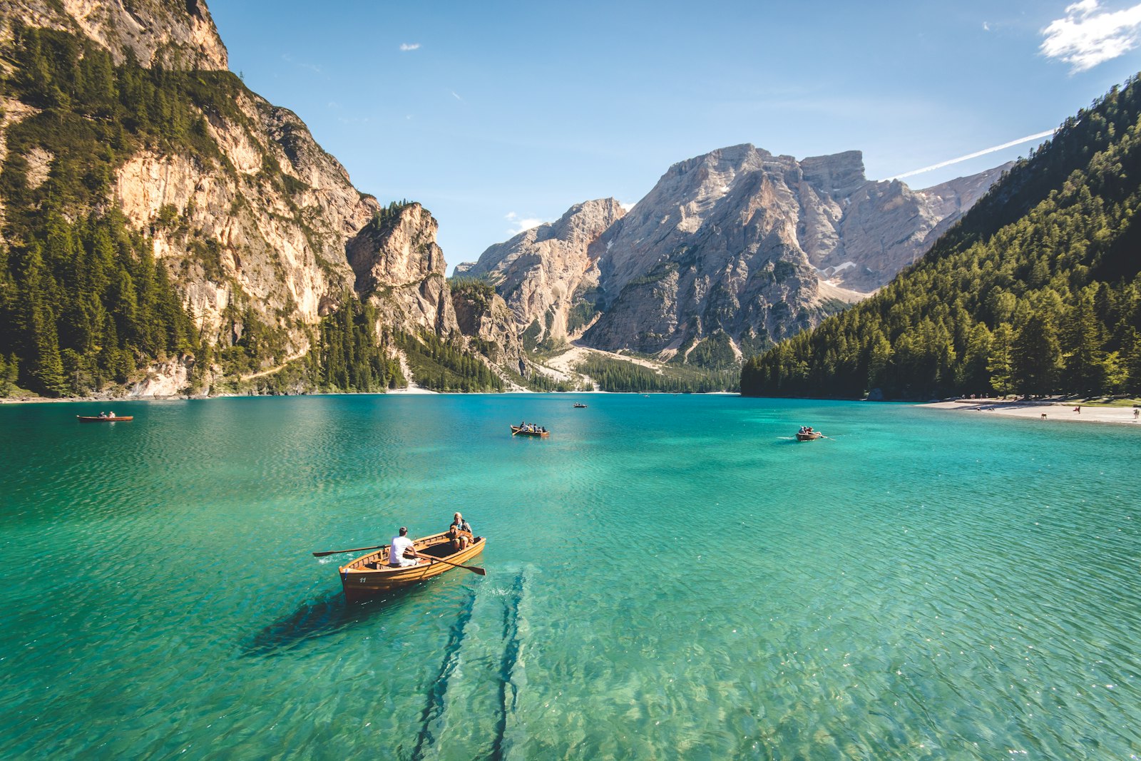 Botes de madera en un lago turquesa entre montañas